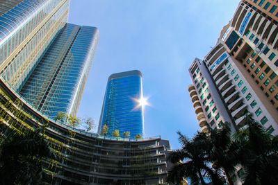 Modern skyscrapers with glass facades reflect sunlight under a clear blue sky.