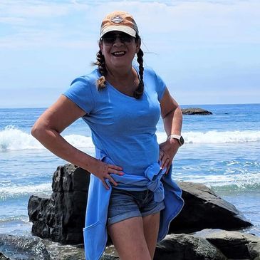 Close up image of a woman at the beach smiling at the camera