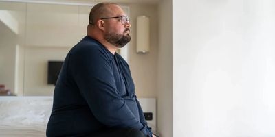 Man sitting while sadly staring out a window