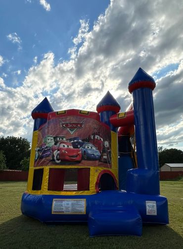 Inflatable bounce house with Cars movie theme under a cloudy sky.