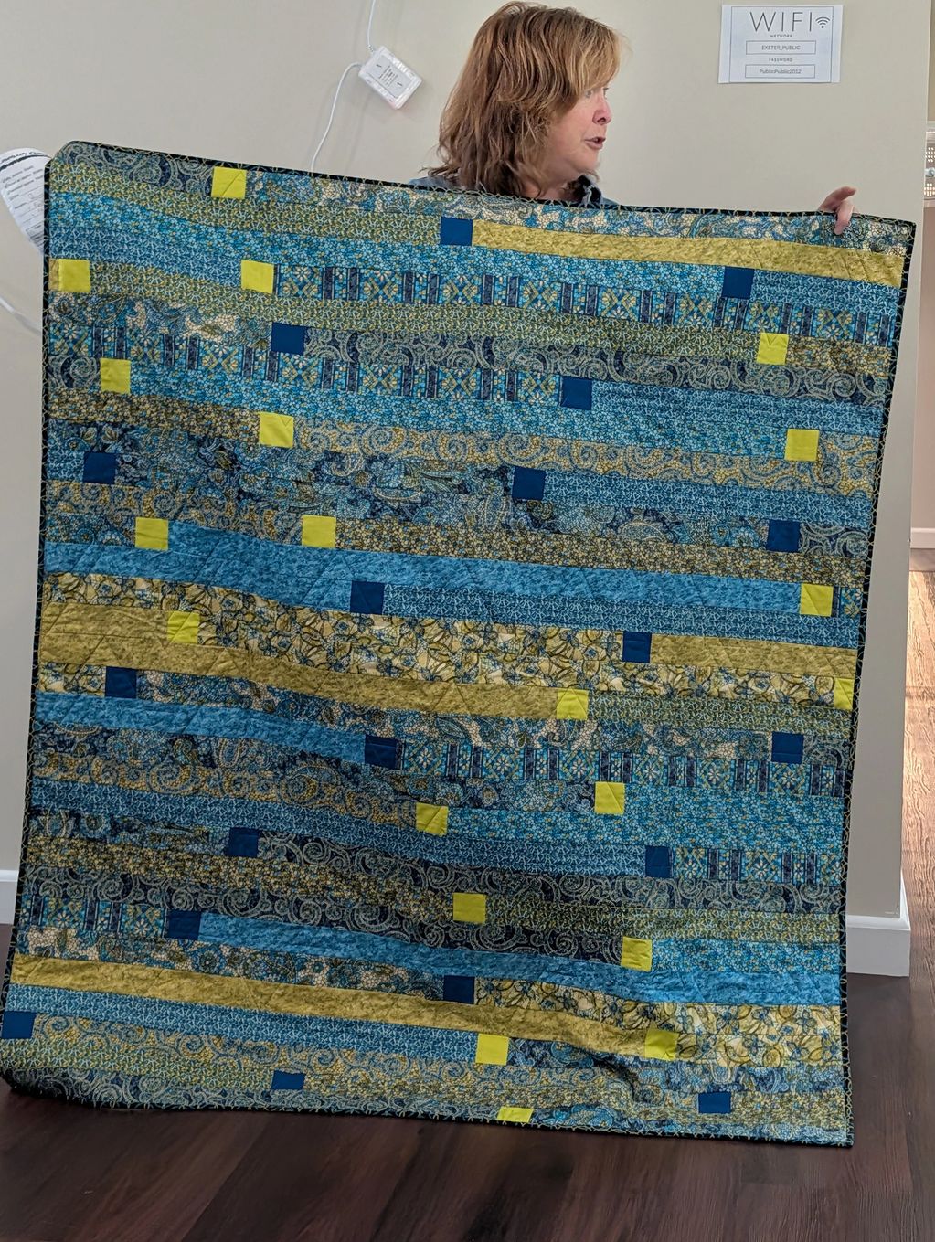 Brenda Scholaro showing quilt made by Kelly Patrick. It was donated to community outreach.