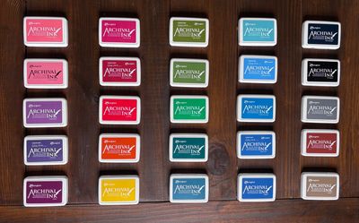 Rows of colorful archival ink pads arranged on a wooden surface.