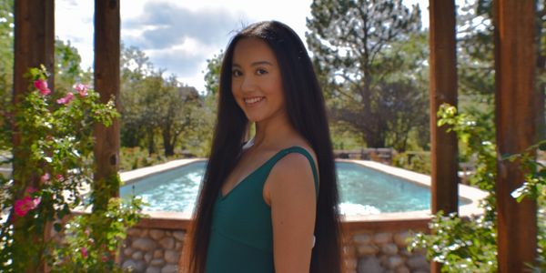 Young woman smiling near a pool on a sunny day.