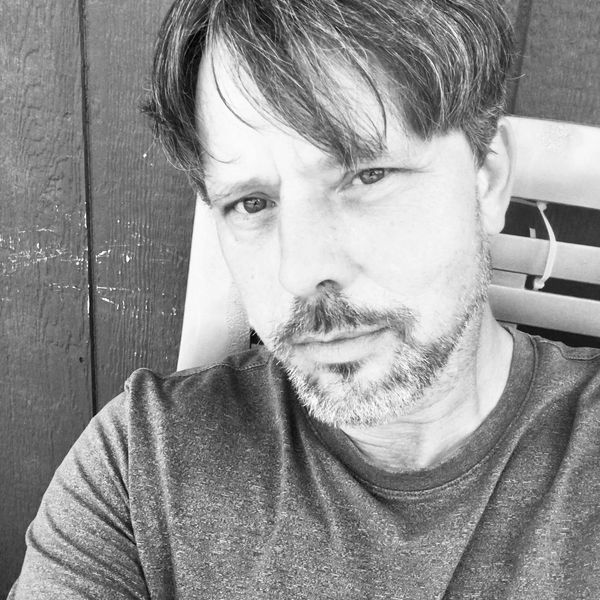 Black and white close-up portrait of a man with a beard and casual shirt.