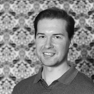 Smiling man in front of patterned backdrop.