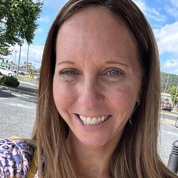 Smiling woman with long brown hair outdoors.