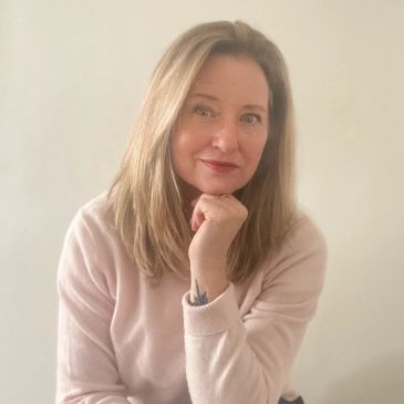 Woman with light brown hair wearing a light pink sweater.