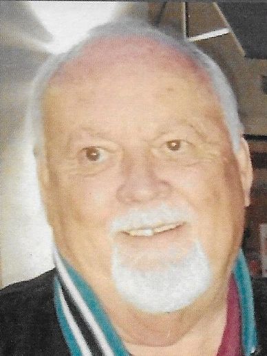 Portrait of an elderly man with white hair and a beard smiling.