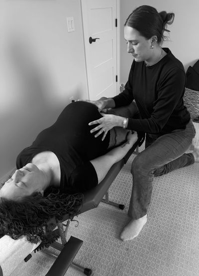 Pregnant woman receiving a prenatal massage from a therapist in a calm room.