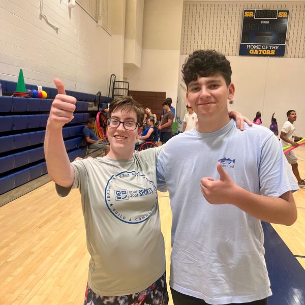 Two young men giving thumbs up in a gym.