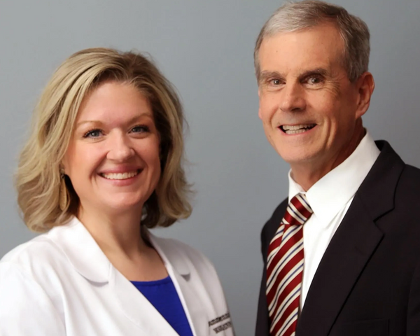 Smiling professionals posing together against a gray backdrop.