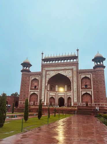 Historic red sandstone monument with intricate white marble inlay under a clear sky.