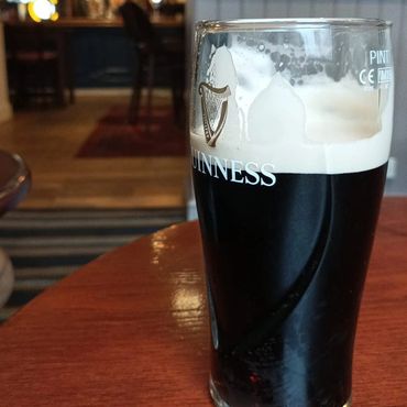 A pint of Guinness beer on a wooden table in a pub.
