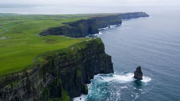 Cliffs of Moher overlooking the Atlantic Ocean with green grass atop.