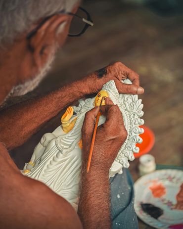 An artist painting a detailed statue of a deity with a brush.