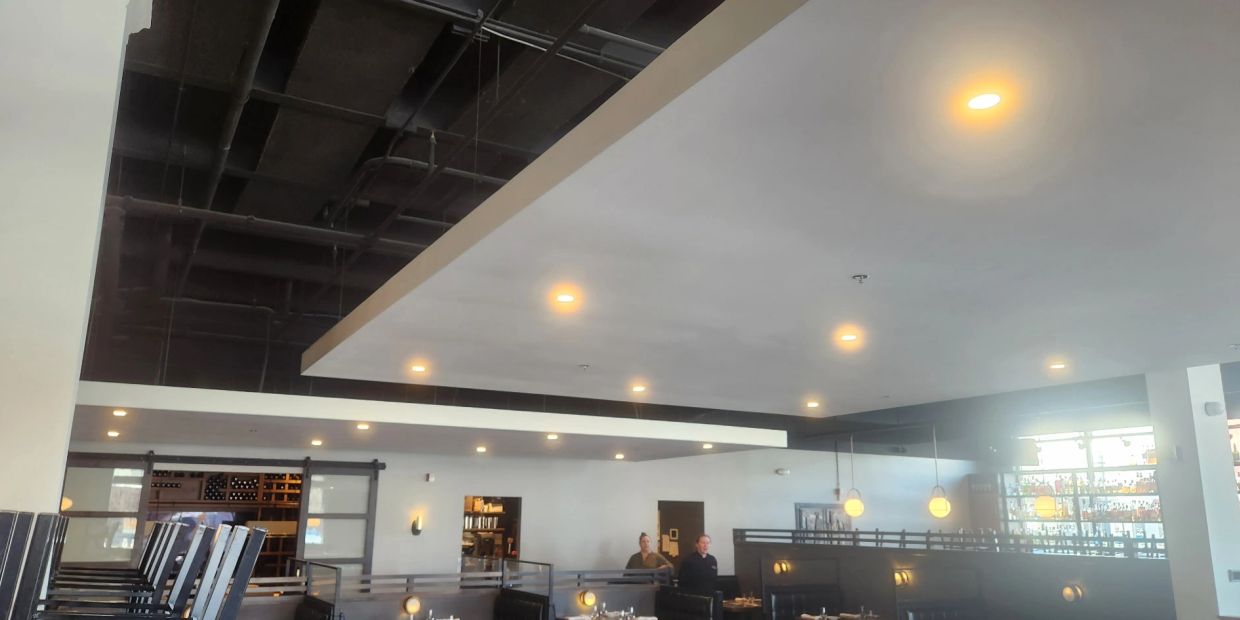Empty restaurant interior with ceiling lights and booths.