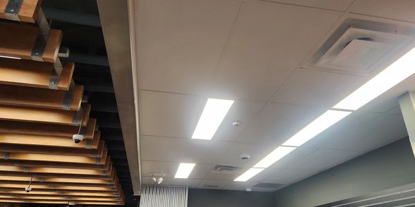 Modern ceiling with wooden beams and fluorescent lights.