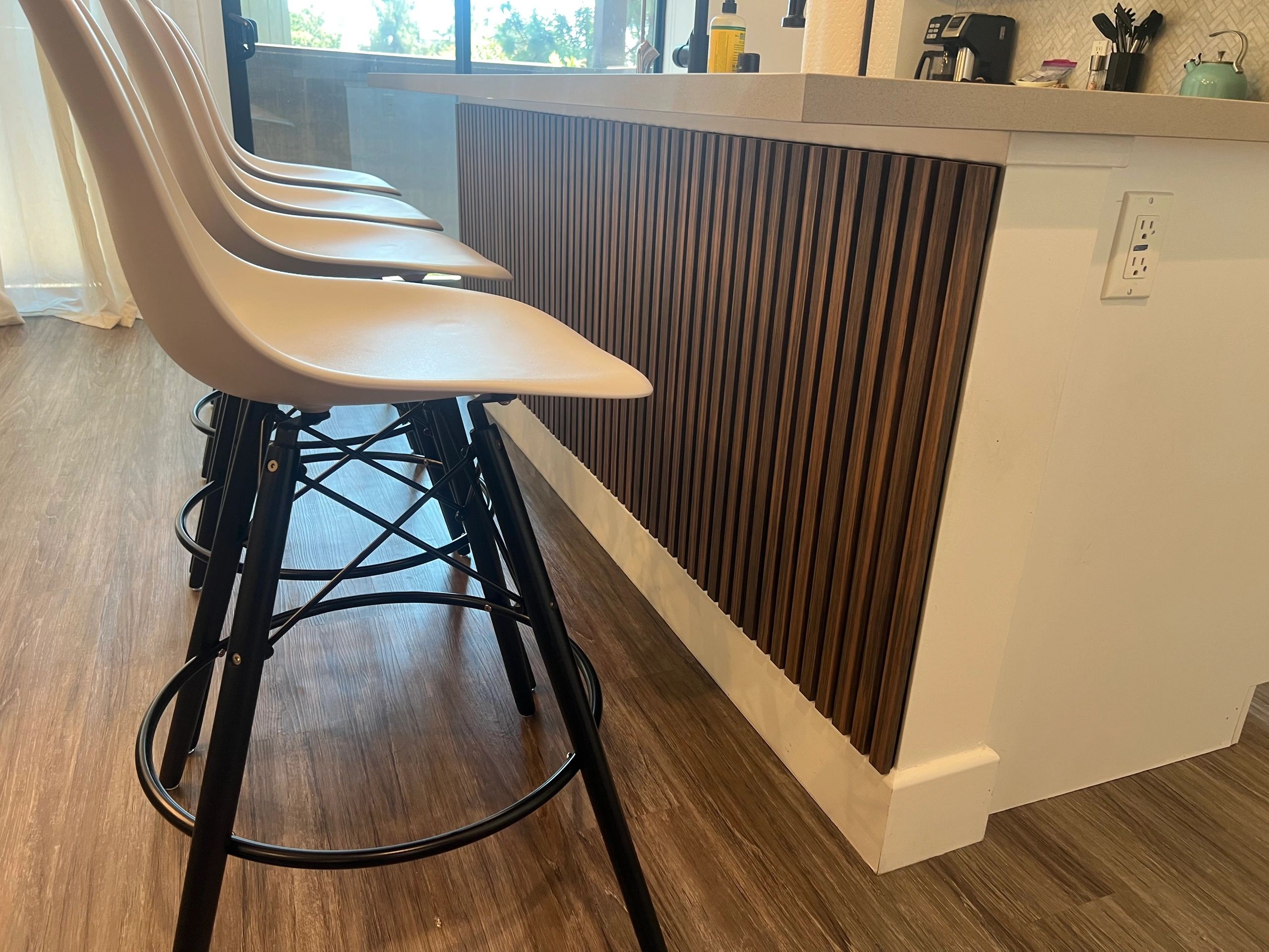 Modern kitchen counter with sleek bar stools and wooden paneling.