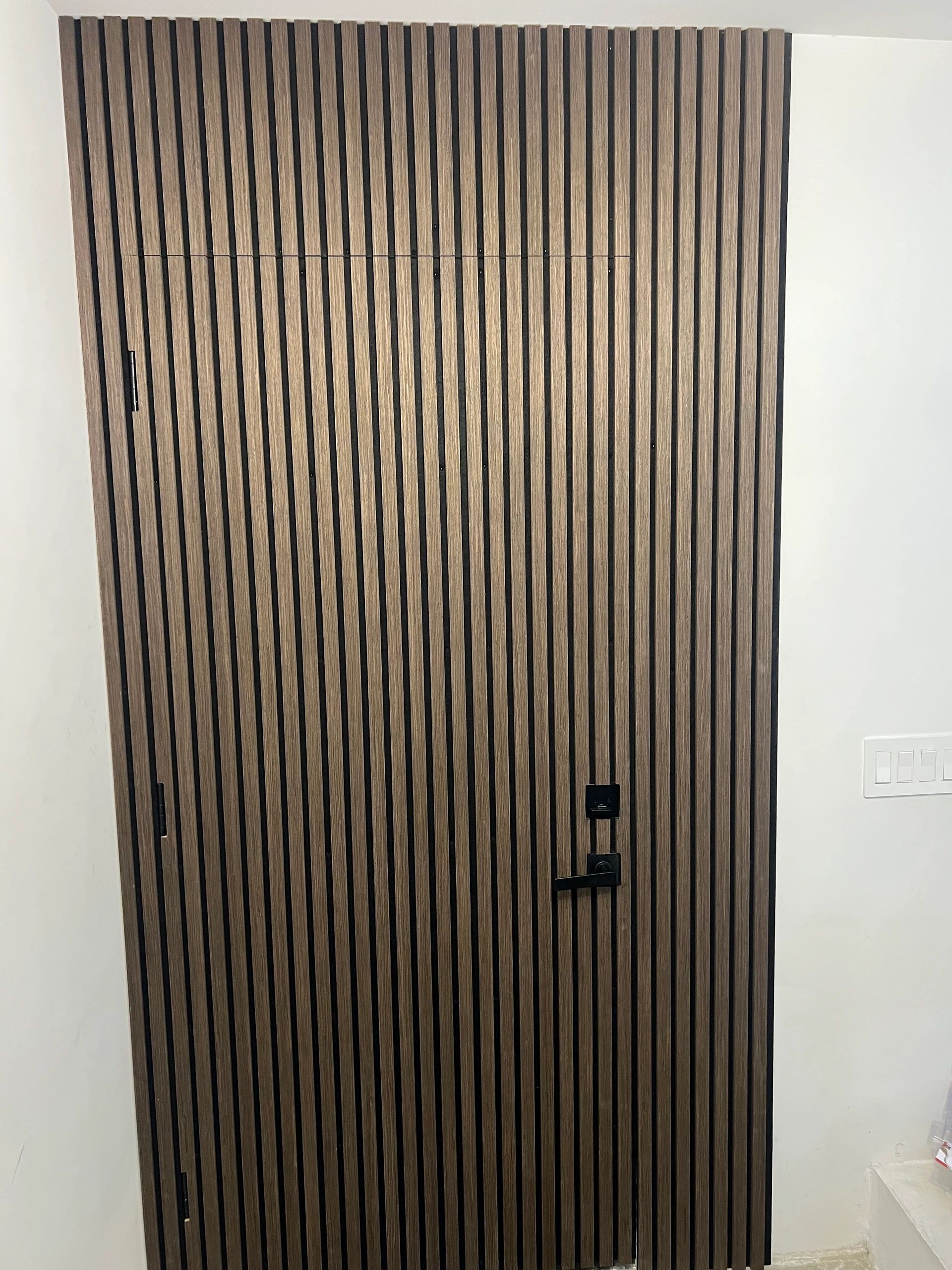 Modern wooden door with vertical slats and black hardware.