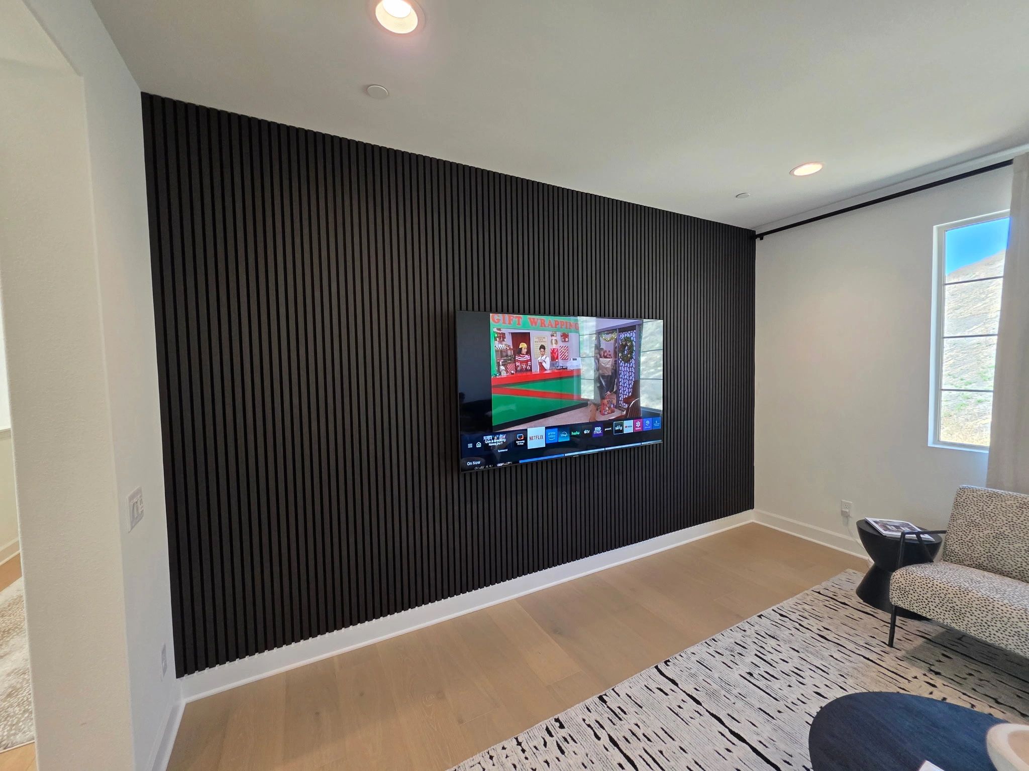 Modern living room with a black slatted accent wall and wall-mounted TV.