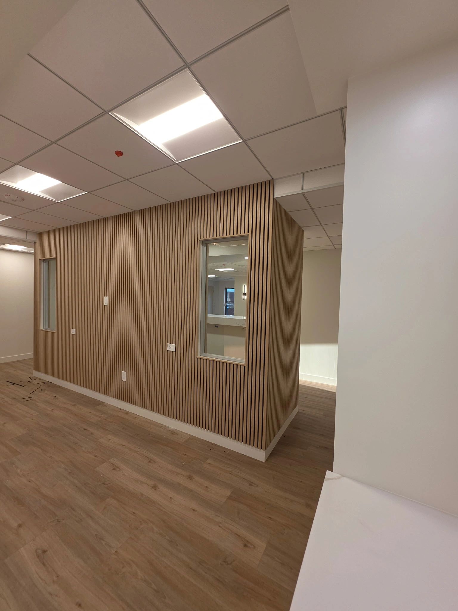 Modern office space with wood-paneled walls and ceiling lights.