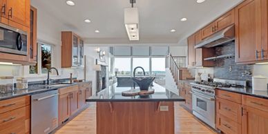 Modern kitchen with wooden cabinets and a central island under bright lighting.