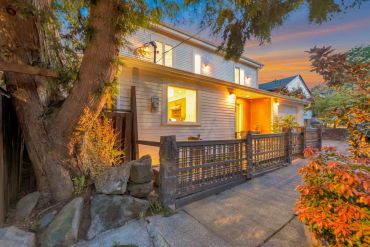 Cozy house with warm lighting at sunset and a stone and metal fence.