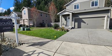 Modern suburban house with a two-car garage and a for-sale sign on the lawn.