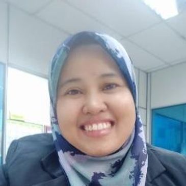 Smiling woman wearing a patterned hijab and black blazer in an office setting.