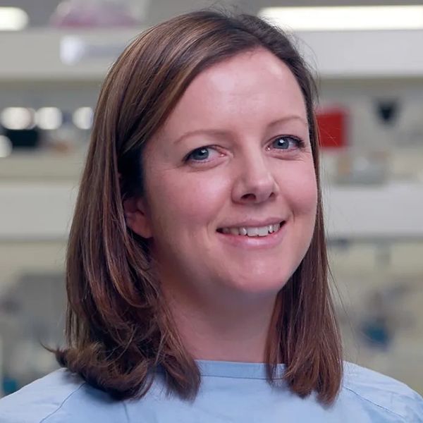 Smiling woman with light brown hair in a light blue shirt.