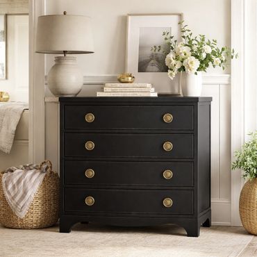 Elegant black dresser with brass handles in a cozy, stylish room.