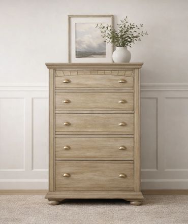 Wooden chest of drawers with a vase and framed art on top.