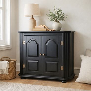Black wooden cabinet with decorative items in a cozy room corner.
