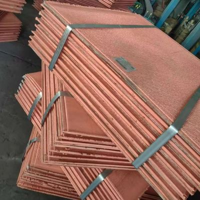 Stacks of copper sheets bundled with metal straps in a warehouse.