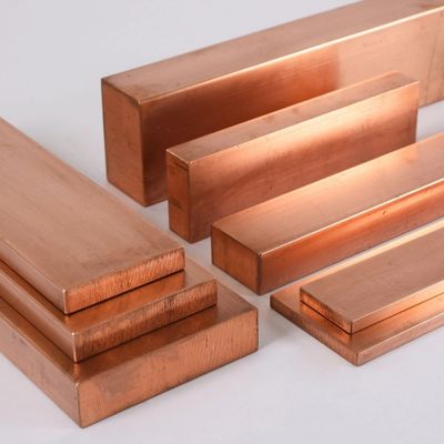Various sizes of polished rectangular copper bars arranged on a white surface.