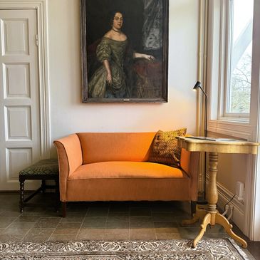 Cozy sitting area with vintage sofa and portrait.