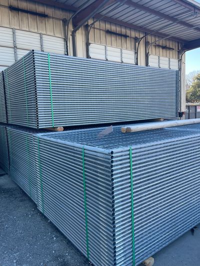 Stacks of metal scaffolding pipes tied with green straps in a warehouse.