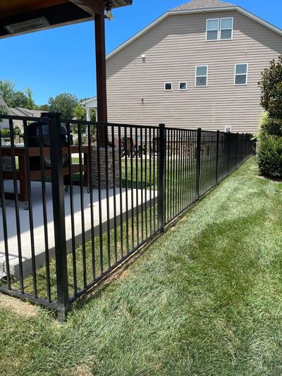 Black metal fence enclosing a patio area in a sunny backyard.