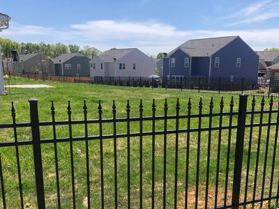 Black metal fence enclosing a green yard in a suburban neighborhood.