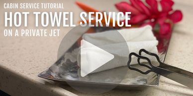 Hot towel service setup on a private jet tray with tongs and flower.