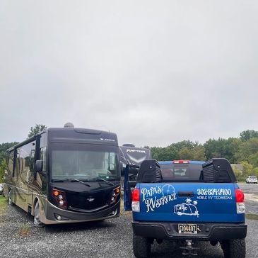A mobile RV technician truck parked beside a large RV on a cloudy day.