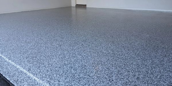 Smooth, speckled epoxy floor in an empty garage space.
