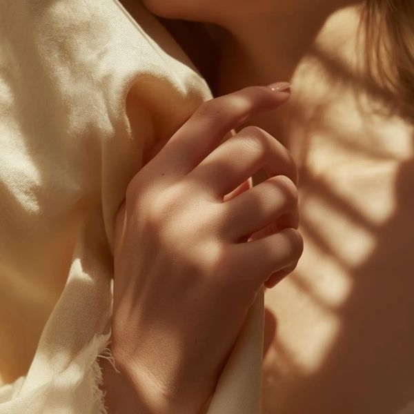 Soft light highlights a hand gently holding fabric.