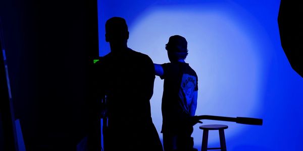 Silhouettes of two people in front of a blue-lit backdrop.