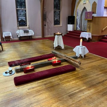 Candles and cushions arranged on wooden floor inside a church.