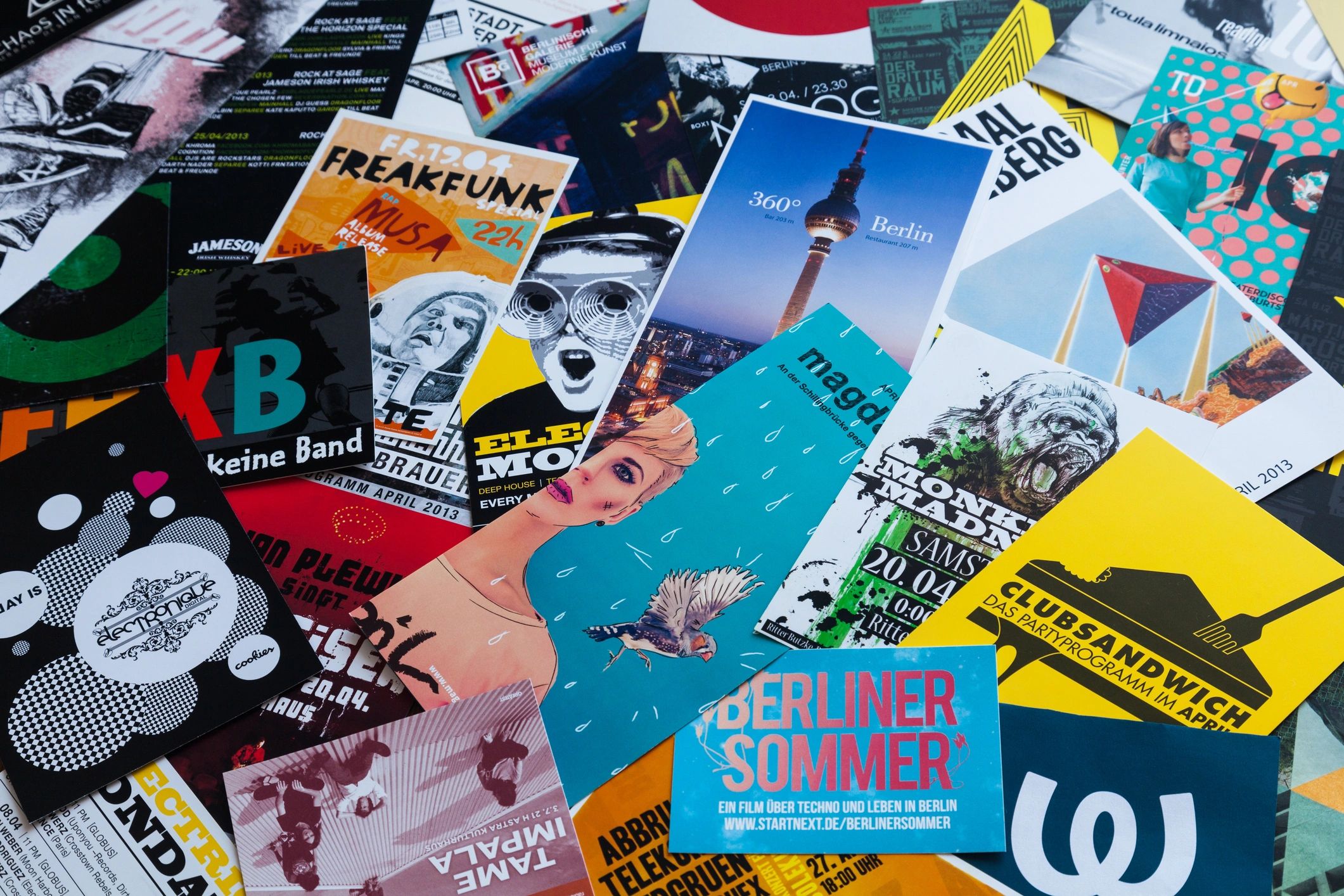 A large variety of printed flyers and cards overlapping each other on a tabletop.