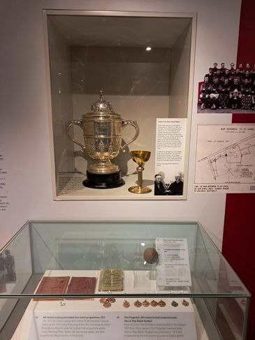Display of trophies, medals, and historical documents in a museum exhibit.