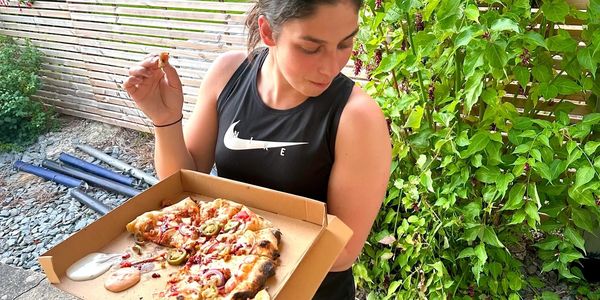 Girl eating pizza from box and looking at dog