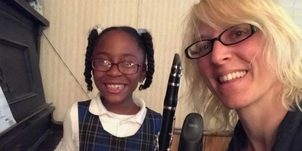 Young piano and clarinet student smiling with teacher in a lesson