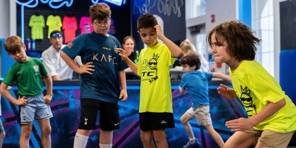 Kids engaged in an indoor activity rallying in colorful shirts.
